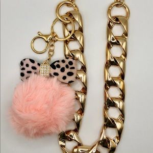 Chunky gold chain link bag strap with fuzzy pink pom pom